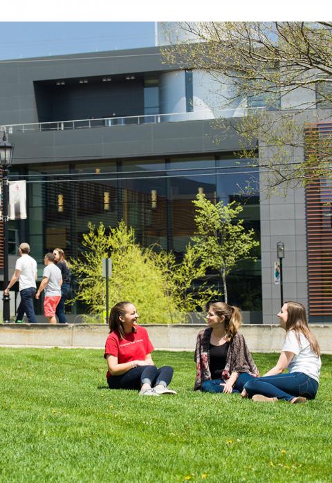 Student relaxing on the grass outside of the Science building